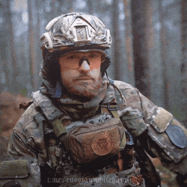 a man with a beard wearing a helmet and goggles is standing in the woods