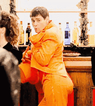 a man in an orange suit is standing in a bar