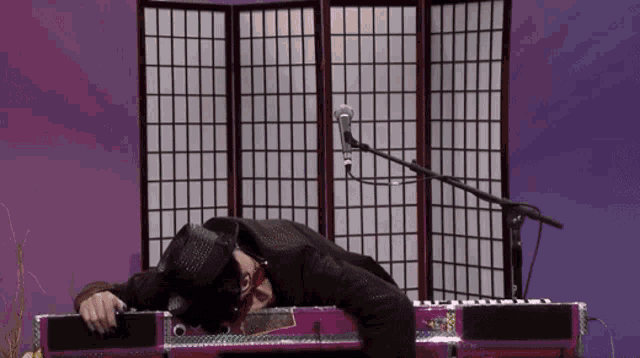a man in a top hat is laying on a pink piano