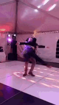 a man is carrying a woman on his shoulders while they dance on a dance floor .