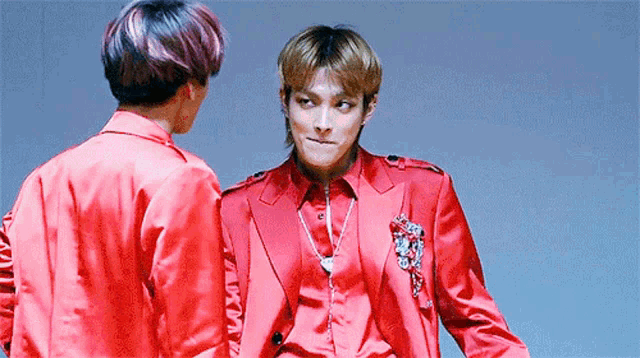 two men in red suits are standing next to each other and talking .