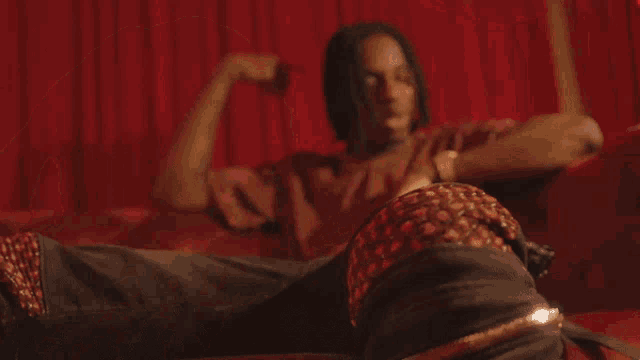 a man in a red shirt is sitting on a red couch