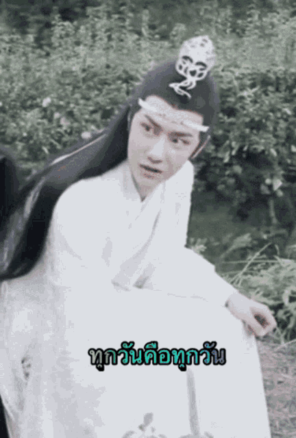 a man in a white robe with a crown on his head is sitting in a field