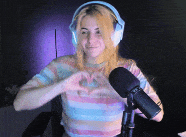 a woman wearing headphones making a heart with her hands in front of a microphone