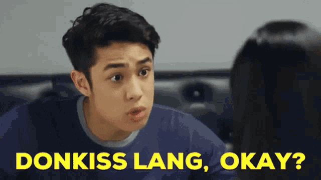 a man in a blue shirt is talking to a woman and the words donkiss lang okay are on the screen