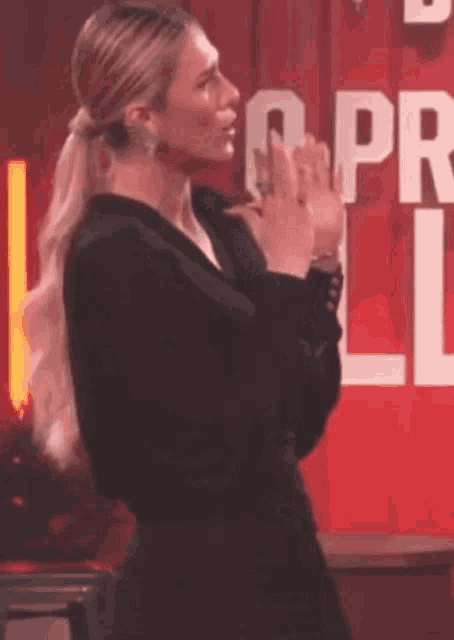 a woman in a black dress is clapping her hands in front of a sign that says lg pr