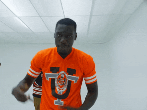 a man is wearing an orange jersey with the letter u on it