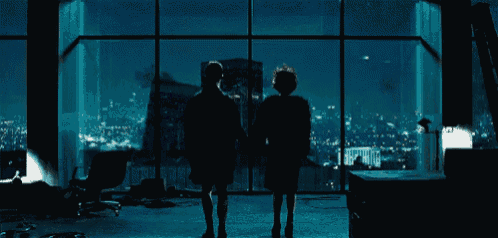 a man and a woman standing in front of a large window