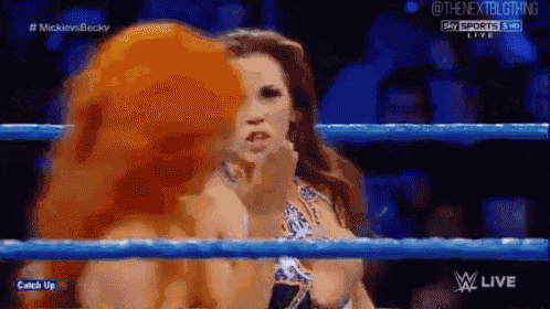 two women are wrestling in a wrestling ring and one of them is licking the other 's face .
