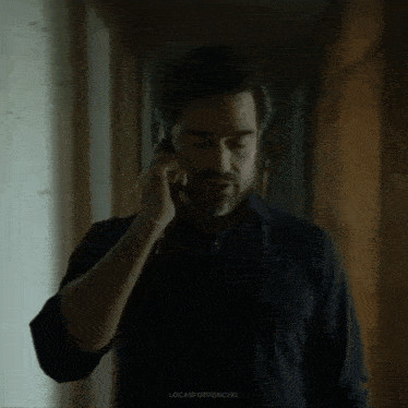 a man in a black shirt is talking on a cell phone .