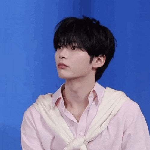 a young man wearing a pink shirt and a white scarf around his neck