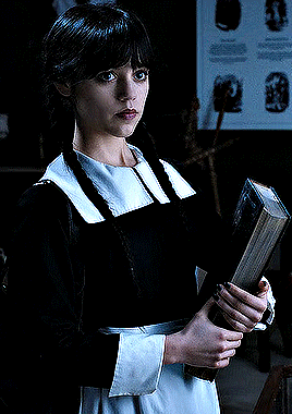 a woman in a black and white dress holds a book