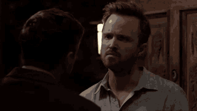 two men are having a fight in a dark room and one of them is making a funny face .