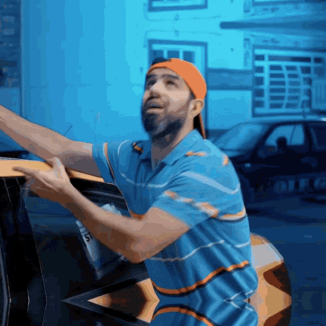 a man in a blue and orange striped shirt is reaching out towards a car that says police on it
