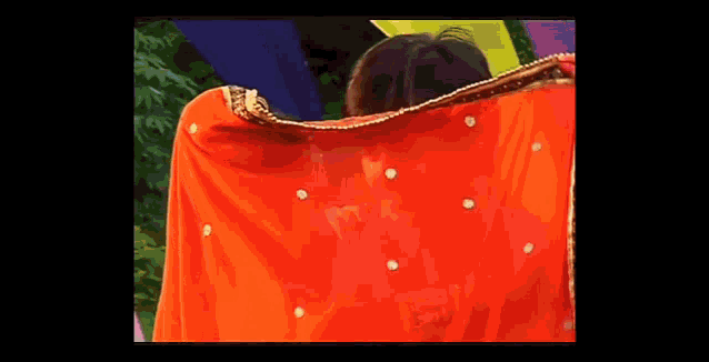 a woman in a red dress is covering her face with a red cloth .
