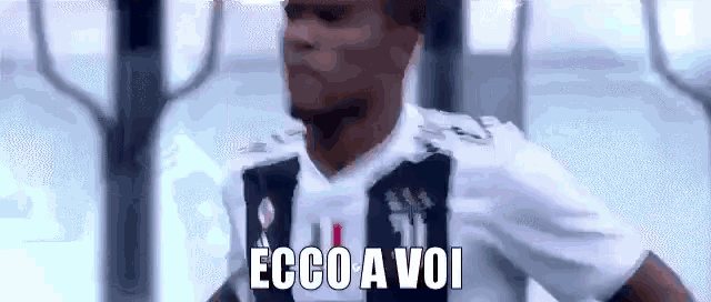 a soccer player wearing a black and white jersey is standing in a stadium and says ecco a voi .
