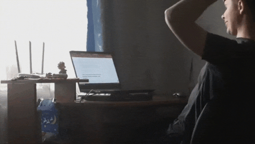 a man is sitting at a desk with a laptop on top of it