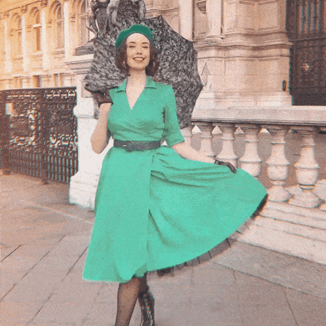 a woman in a green dress and beret holds an umbrella