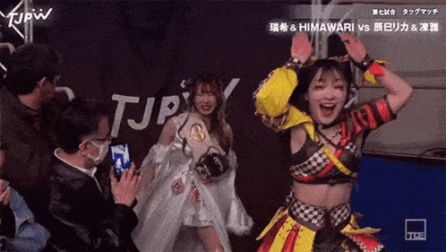 two women are dancing in front of a tjpw sign