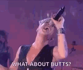 a woman is singing into a microphone while laughing and saying what about butts ?