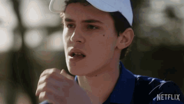 a man wearing a white hat and a blue shirt with netflix written on the bottom