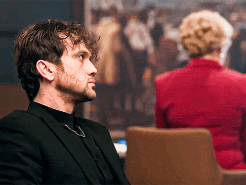 a man in a suit is sitting in front of a woman in a red shirt