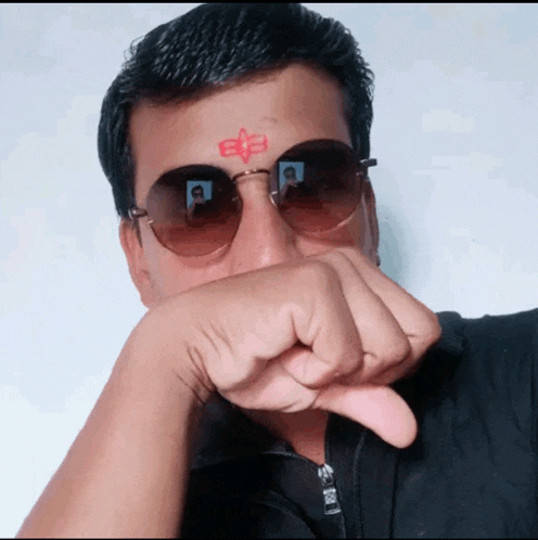 a man wearing sunglasses has a red symbol on his forehead with the letter e on it