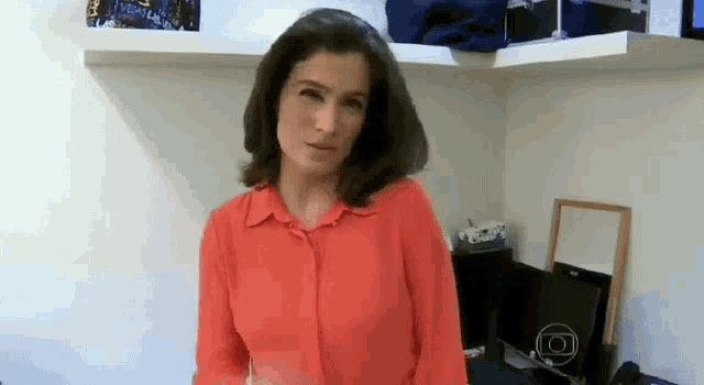 a woman in a red shirt is standing in a room with a computer .
