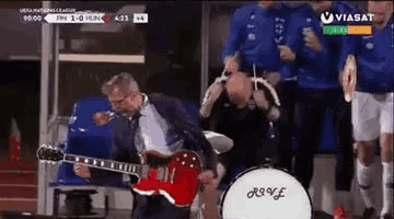 a man in a suit is playing a guitar in front of a drum that says ' hoff ' on it