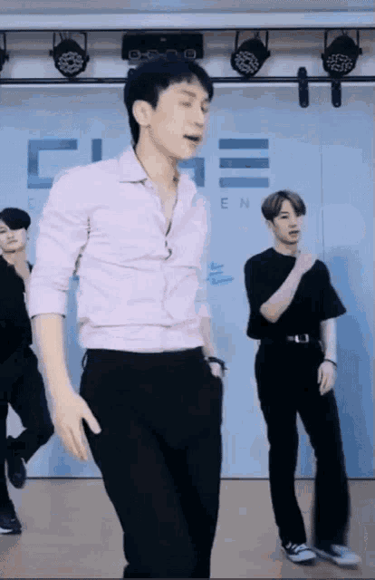 a man in a white shirt is dancing in front of a wall that says cube