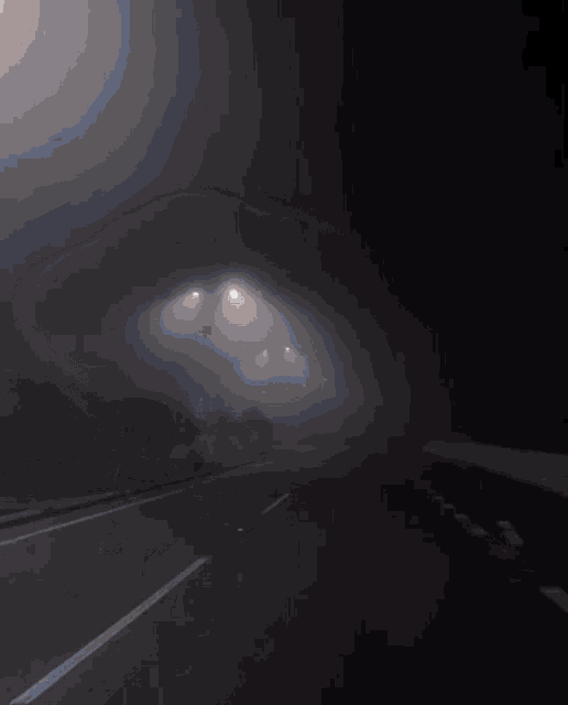 a foggy highway with a few street lights on