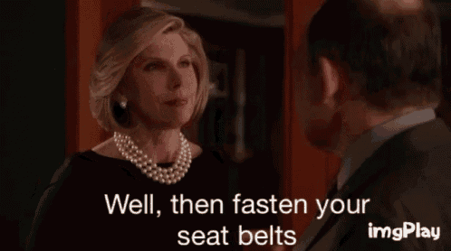 a woman in a pearl necklace talks to a man in a suit