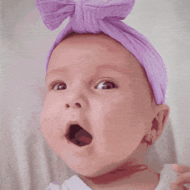 a baby wearing a purple headband and earrings