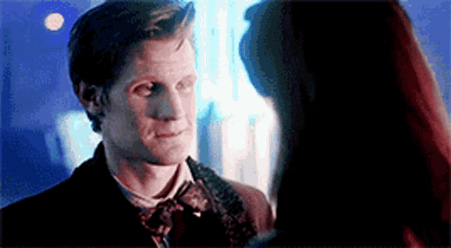 a man and woman are looking at each other in a dark room .