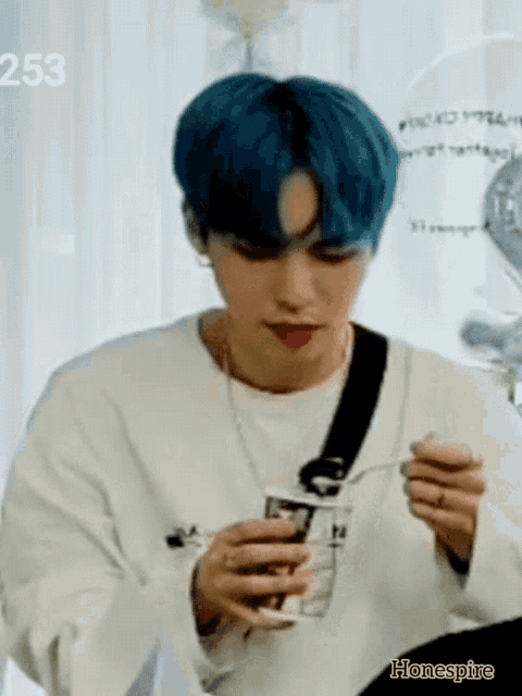 a young man with blue hair is eating something with a spoon