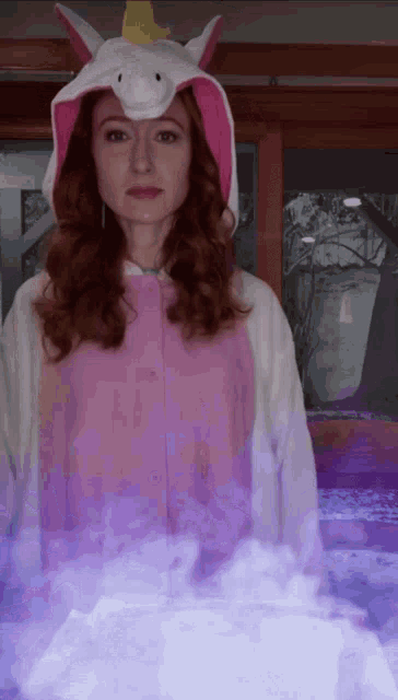 a woman wearing a unicorn costume is standing in front of a window