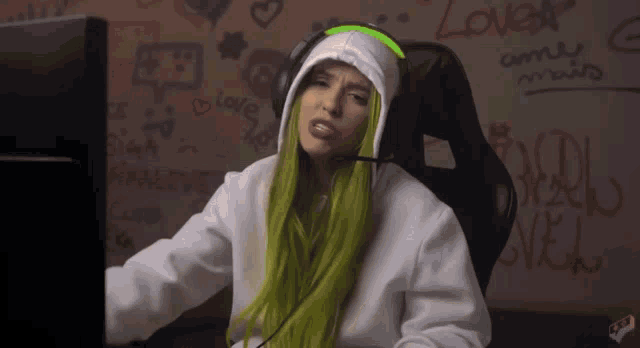 a woman with green hair is sitting in front of a computer screen