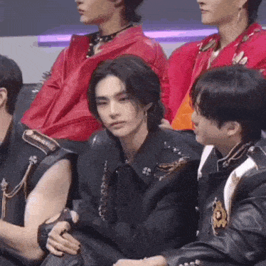 a group of young men are sitting next to each other in a row .
