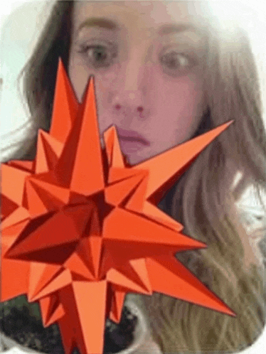 a woman is holding a red star in front of her face