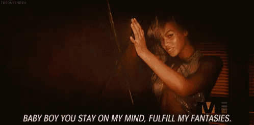 a woman is singing in a dark room with the words `` baby boy you stay on my mind , fulfill my fantasies . ''