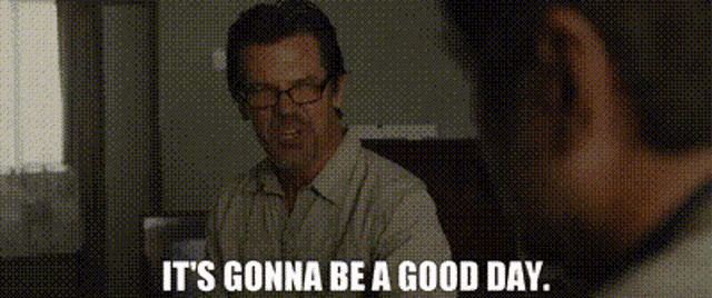 a man wearing glasses is sitting at a table with the words `` it 's gonna be a good day ''