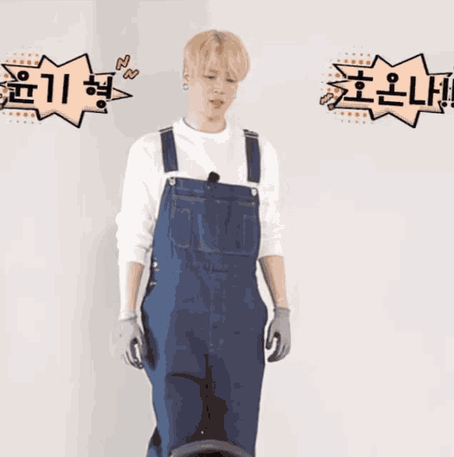 a man in overalls is standing in front of a white wall with chinese writing on it