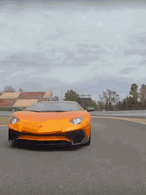 an orange lamborghini is driving down a track