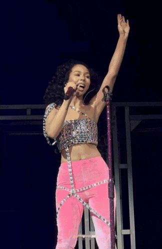 a woman in pink pants and a silver top stands on a stage