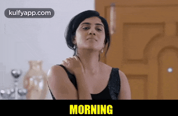 a woman in a black tank top is holding her shoulder and the word morning is on the bottom of the image .