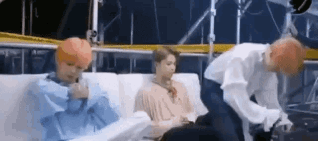 a group of people are sitting on a couch talking on a cell phone .