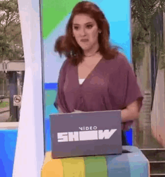 a woman stands behind a laptop that says show on it