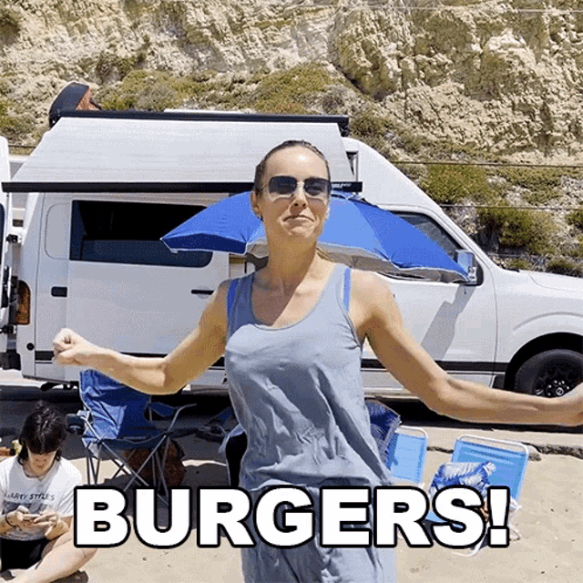 a woman standing in front of a van with a blue umbrella and the words burgers written on the bottom