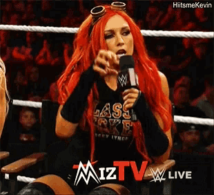 a woman with red hair is holding a microphone in a wrestling ring ..
