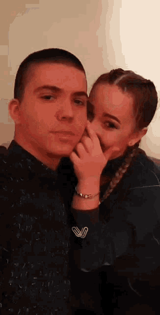a man and a woman are posing for a picture and the woman is covering the man 's nose .